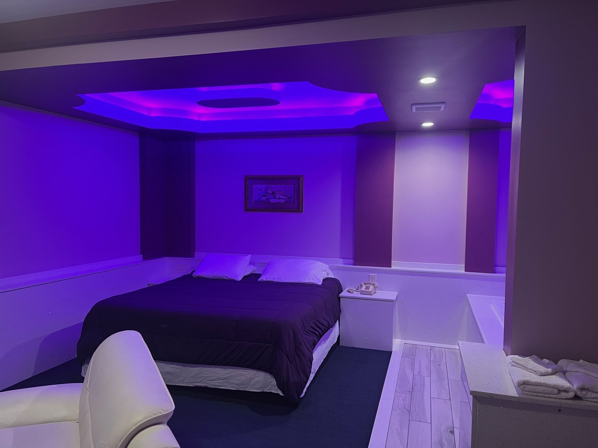 Un dormitorio moderno con cama, mesita de noche y un cuadro enmarcado en la pared.