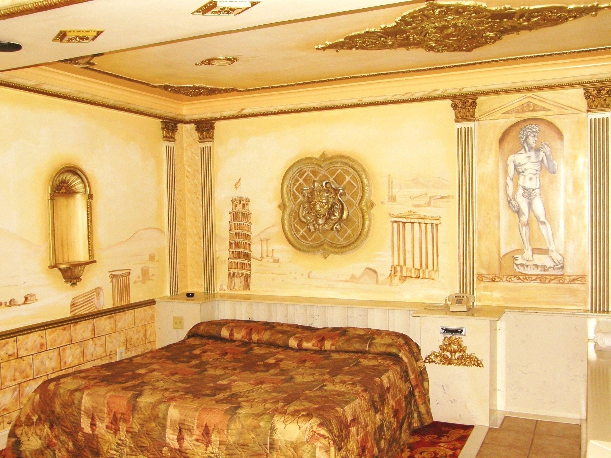 A luxurious bedroom with a large bed, ornate wall decorations, and classical architectural elements.