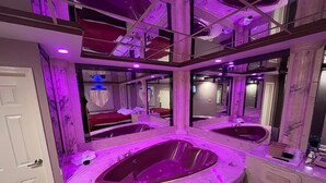A luxurious bathroom with a large freestanding bathtub, multiple mirrors, and a checkered floor pattern.