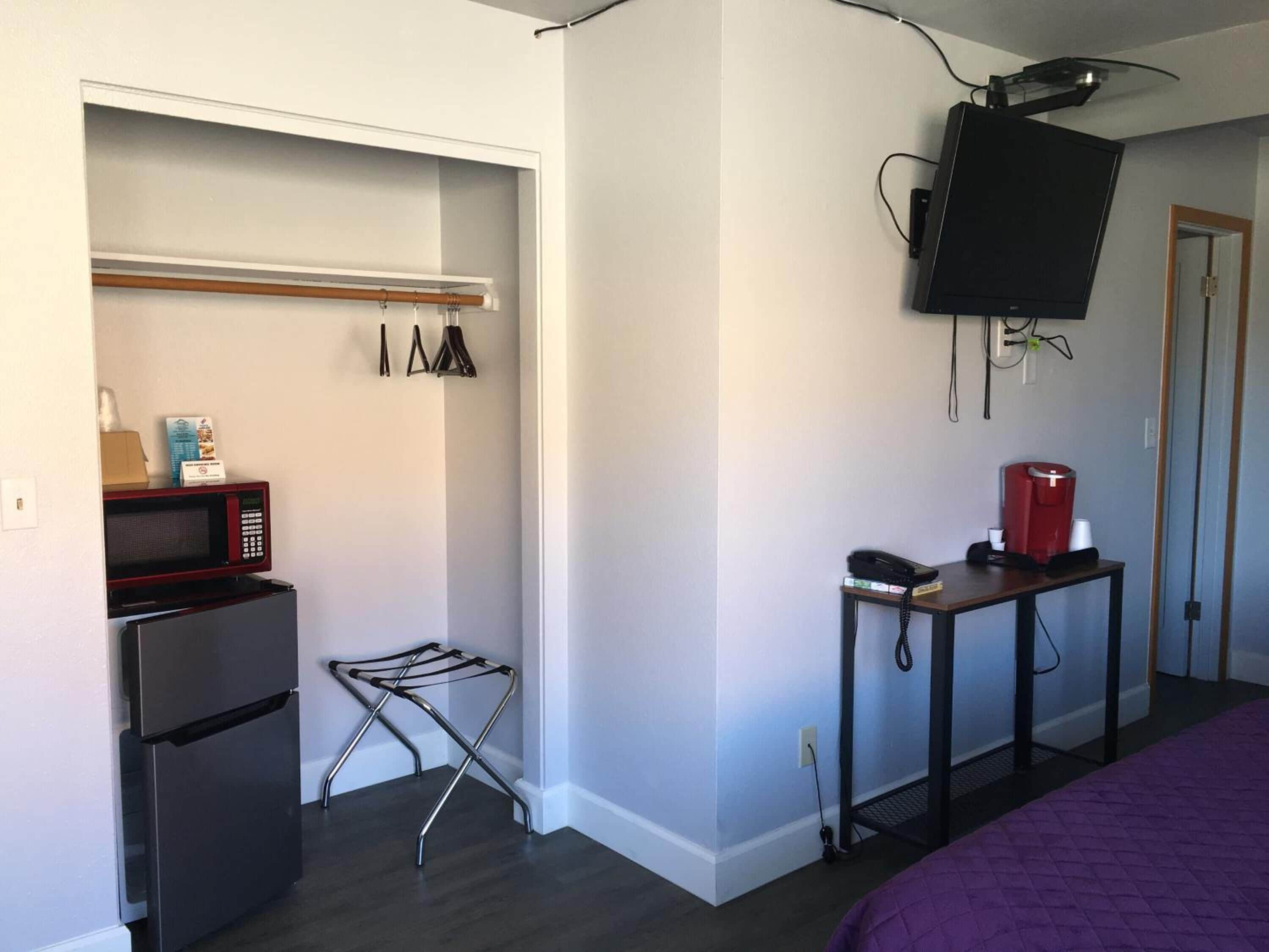 A compact room with a kitchenette, including a refrigerator, microwave, and coffee maker.