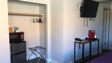 A compact room with a kitchenette, including a refrigerator, microwave, and coffee maker.
