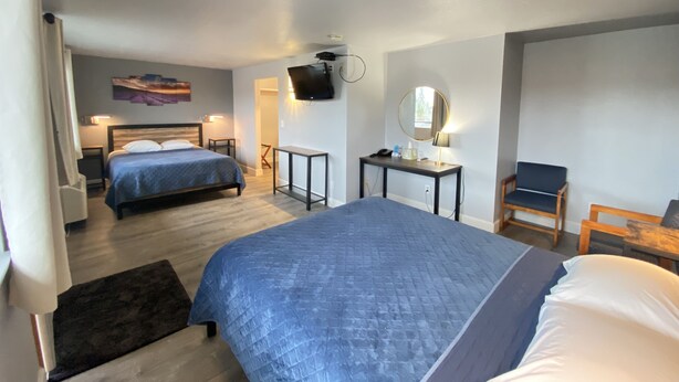 Ein Hotelzimmer mit zwei Betten, einem Schreibtisch, einem Stuhl, einem Fernseher und einem Spiegel.