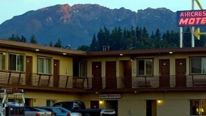 Ein Motel mit einem Schild, auf dem 'AIRCREST MOTEL' steht, vor einer Bergkulisse.