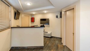 A hallway with a reception desk, a flat-screen TV, a fire extinguisher, and a door. - Rodeway Inn Chicago - Evanston (Chicago)