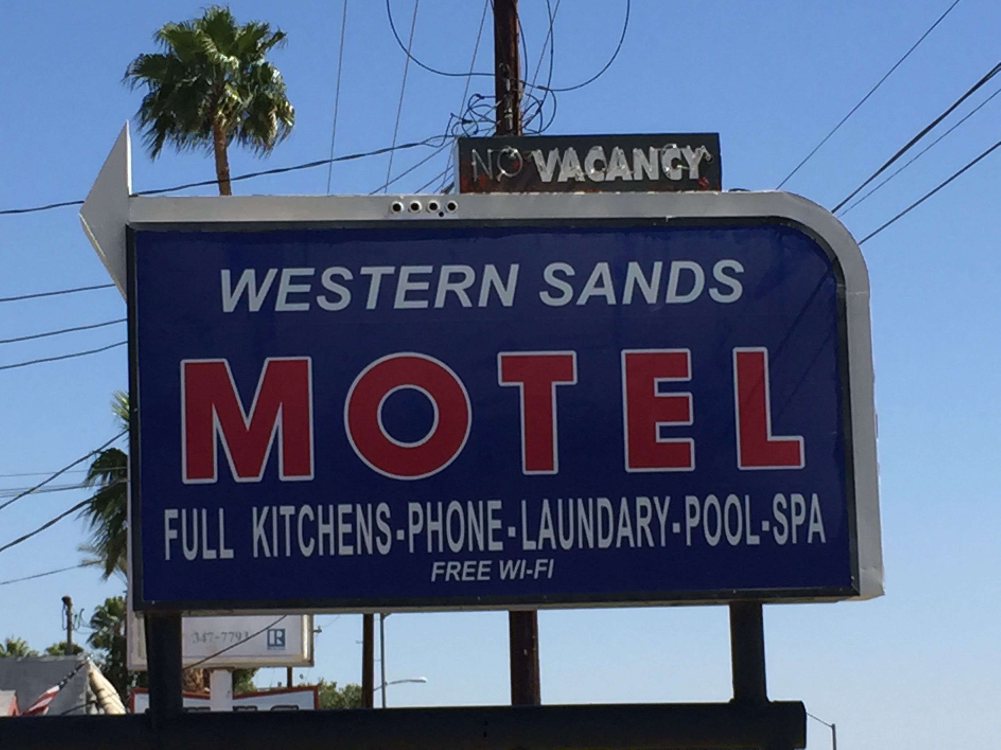 A motel sign with amenities including full kitchens, phone, laundry, pool, and spa, and free Wi-Fi.