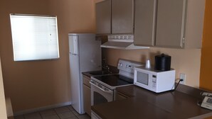 A compact kitchen with a refrigerator, stove, microwave, and a small sink. - Western Sands Motel (Indio)
