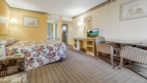 Een hotelkamer met een bed, een bureau, een stoel en een televisie.