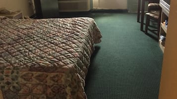 A hotel room with a bed, a desk, a chair, and a wardrobe.