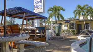 Un motel Shell con piscina climatizada, mobiliario exterior y palmeras.