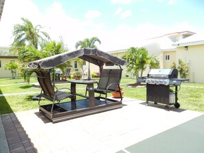 An outdoor patio with a grill, a covered seating area, and a small table. - Shell Motel (Hollywood)