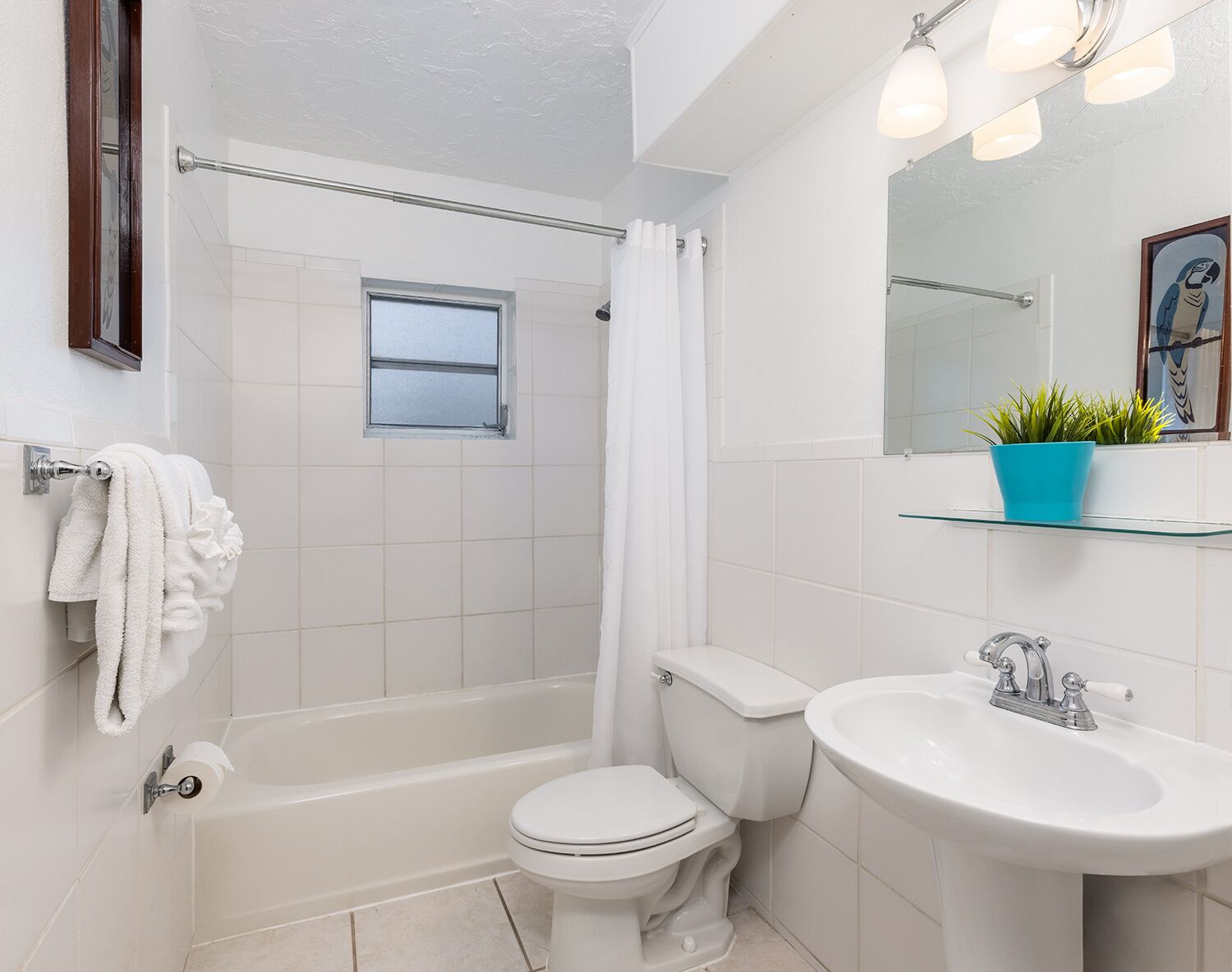 A bathroom with a bathtub, toilet, sink, and a window.