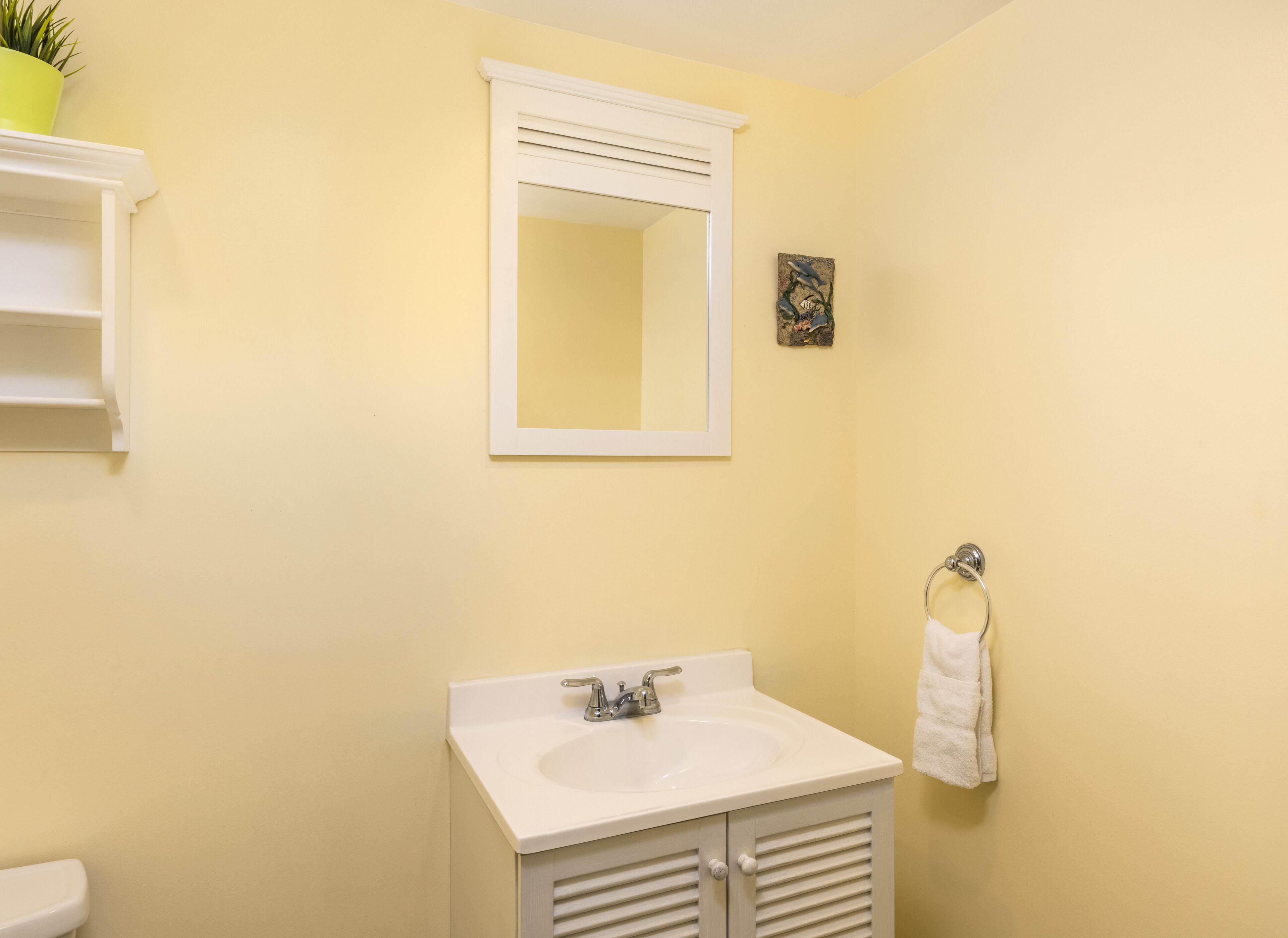 A bathroom with a white sink, a mirror, and a towel rack.