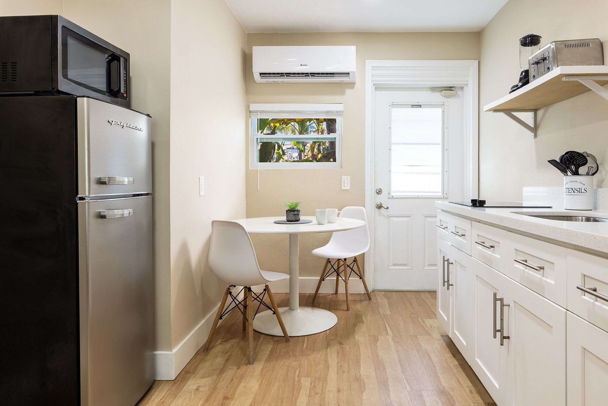 Une cuisine compacte équipée d’un réfrigérateur, d’un four à micro-ondes et d’une petite table à manger avec des chaises.