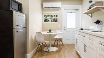 Une cuisine compacte équipée d’un réfrigérateur, d’un four à micro-ondes et d’une petite table à manger avec des chaises.