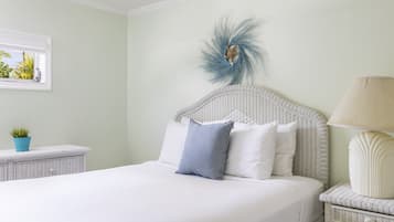 A neatly made bed with white bedding, a wicker headboard, and a decorative feather accent.