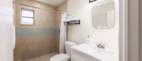 A bathroom with a shower, toilet, and sink.