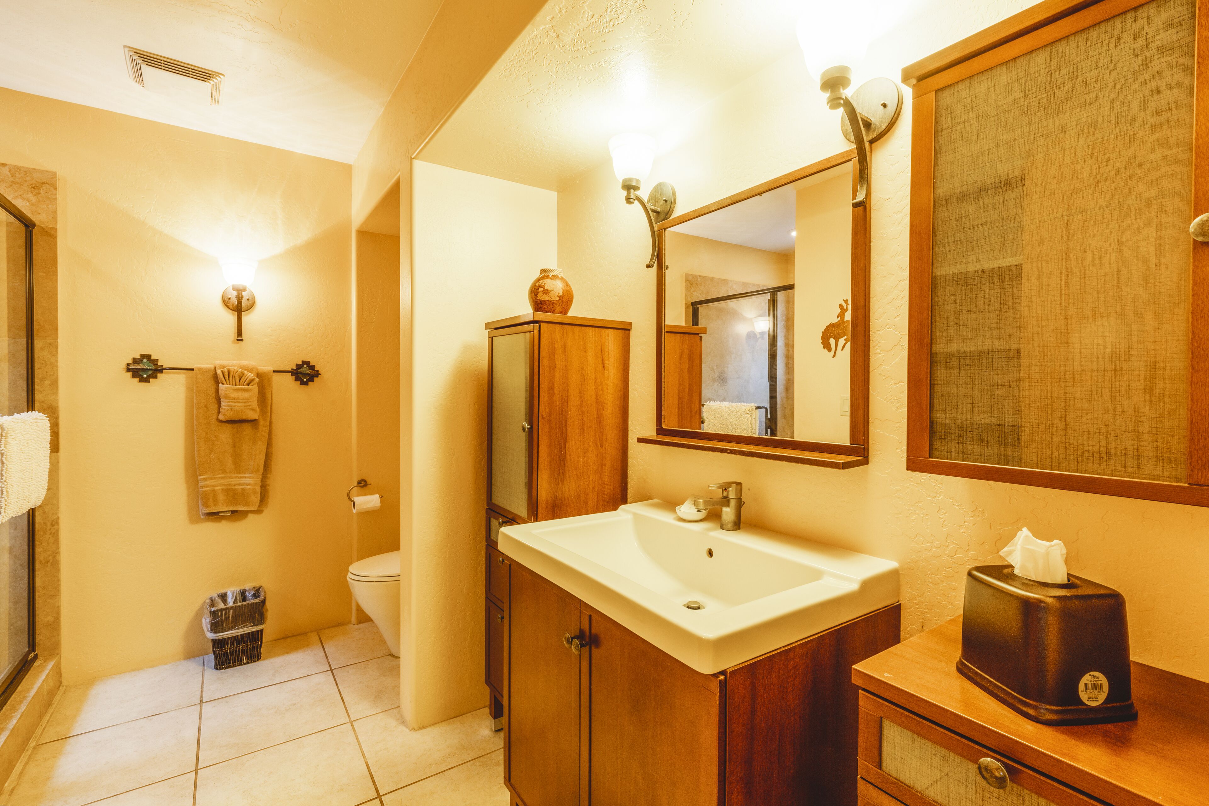 A bathroom with a wooden vanity, a mirror, a sink, and a towel rack.