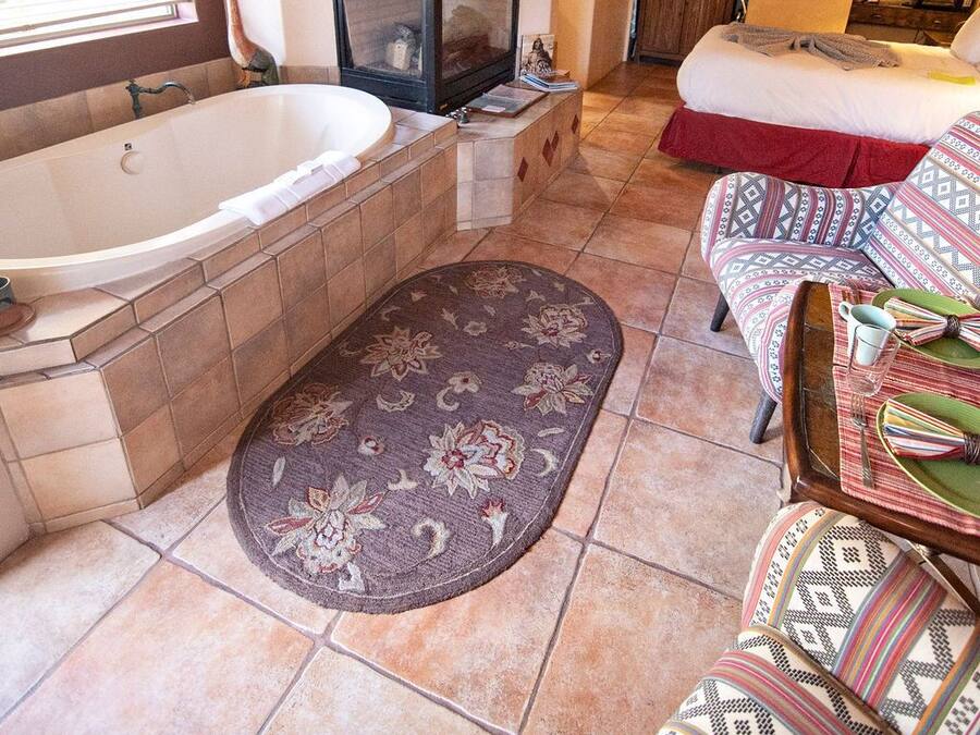 Amplia sala de estar con una bañera grande, chimenea, sofá y alfombra estampada.