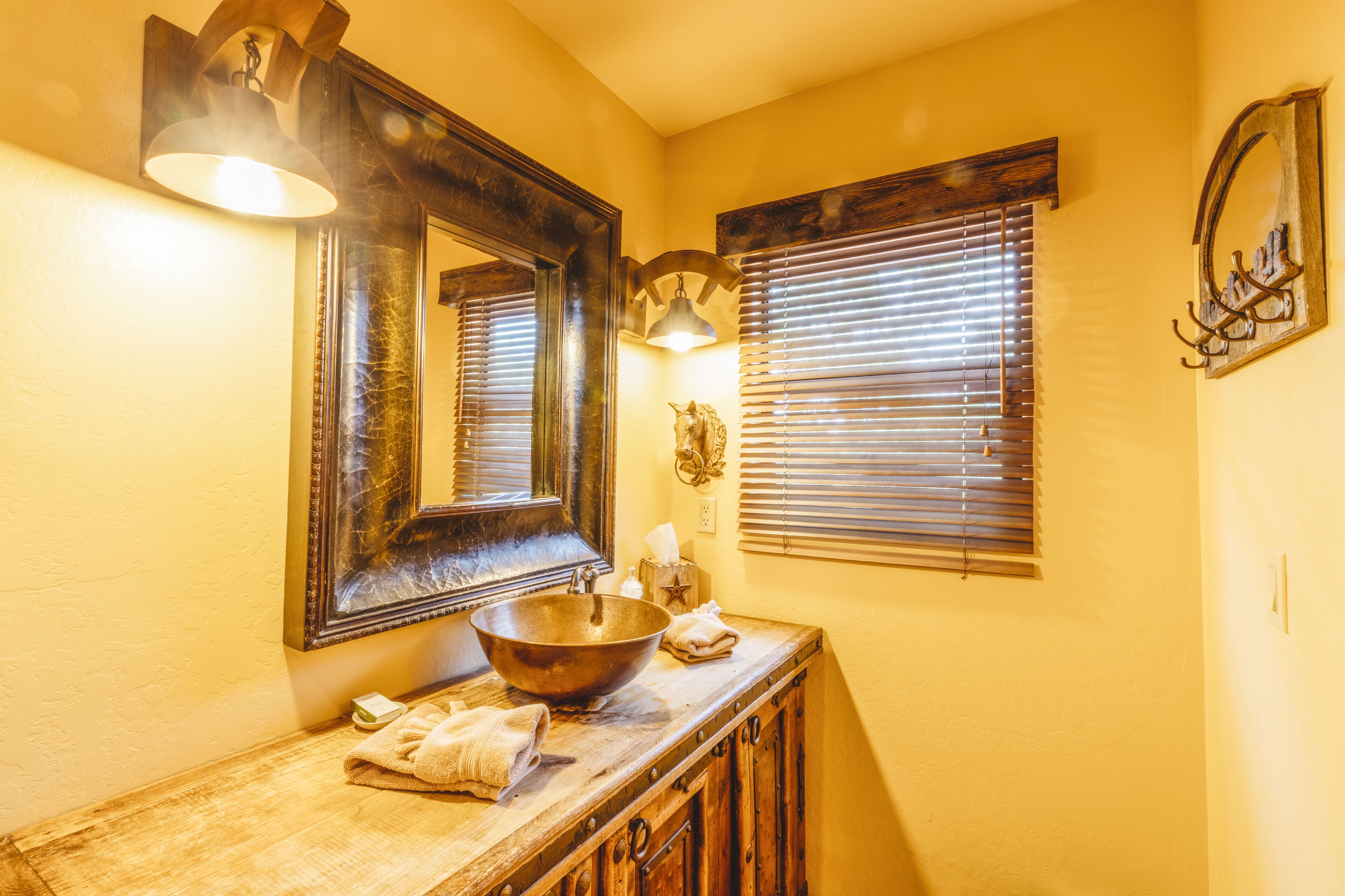 A bathroom with a wooden vanity, a large mirror, and a bowl sink.