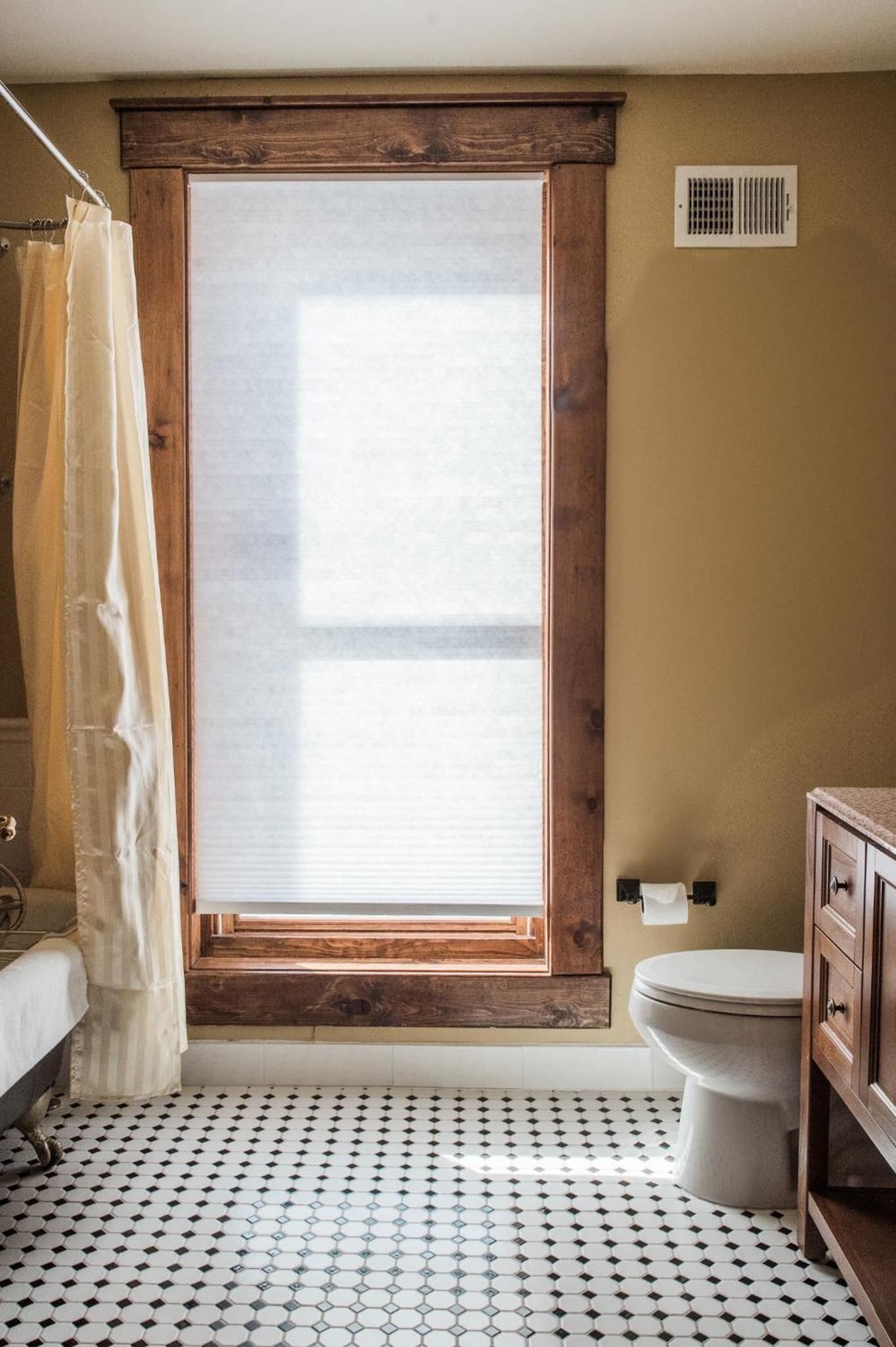 A bathroom with a large window, a toilet, and a bathtub.