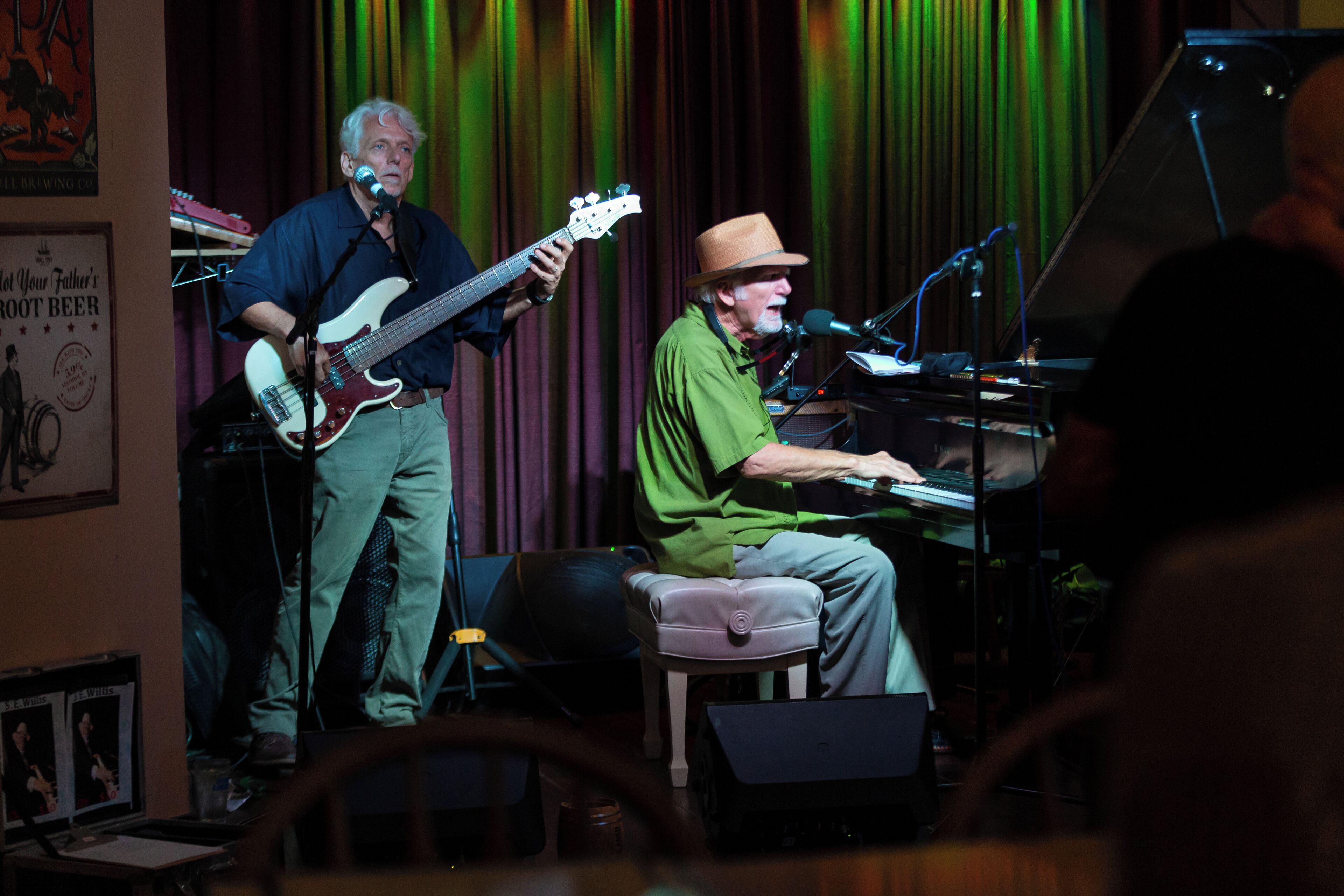 A band performing on stage with musical instruments and a piano.