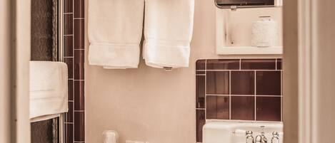 A bathroom with a toilet, sink, and a mirror above the sink. There are towels hanging on a rack.