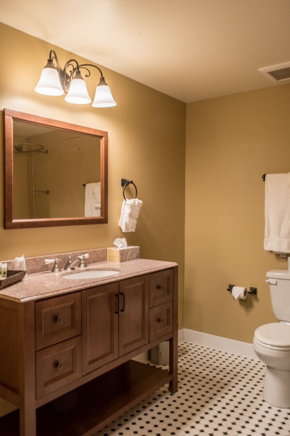 A bathroom with a wooden vanity, a large mirror, and a toilet.