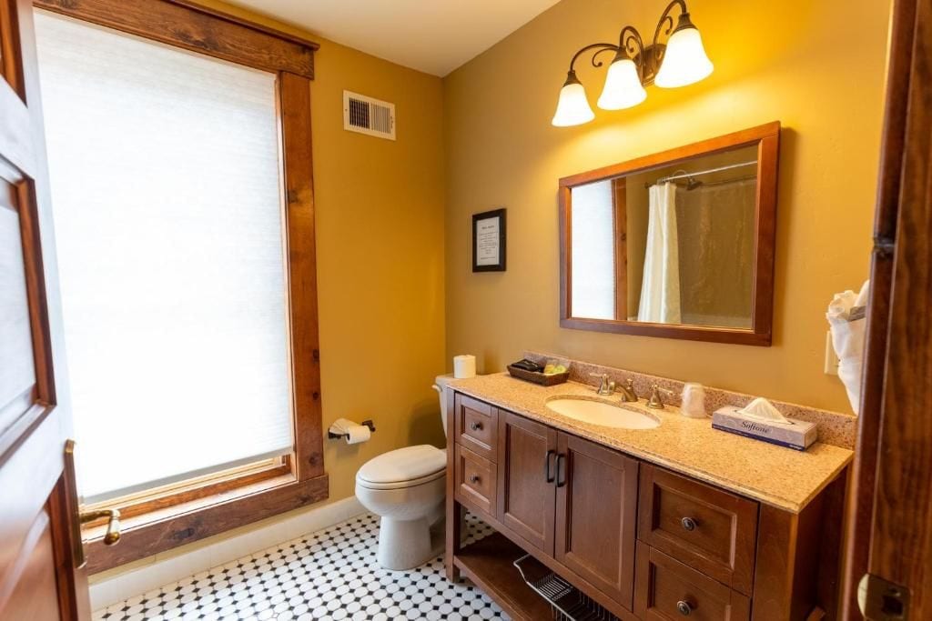 Un bagno con il water, un lavandino, un mobile lavabo e una finestra.