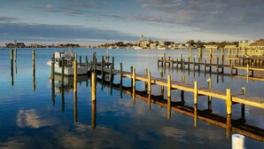 A marina with wooden docks extending into calm water, a small boat docked at the pier, and buildings in the background. - Ocracoke Harbor Inn (Ocracoke)