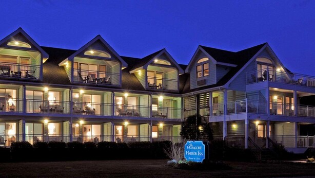A multi-story hotel with balconies and large windows, a sign indicating it is the Harbor Inn, and a well-lit exterior. - Ocracoke Harbor Inn (Ocracoke)