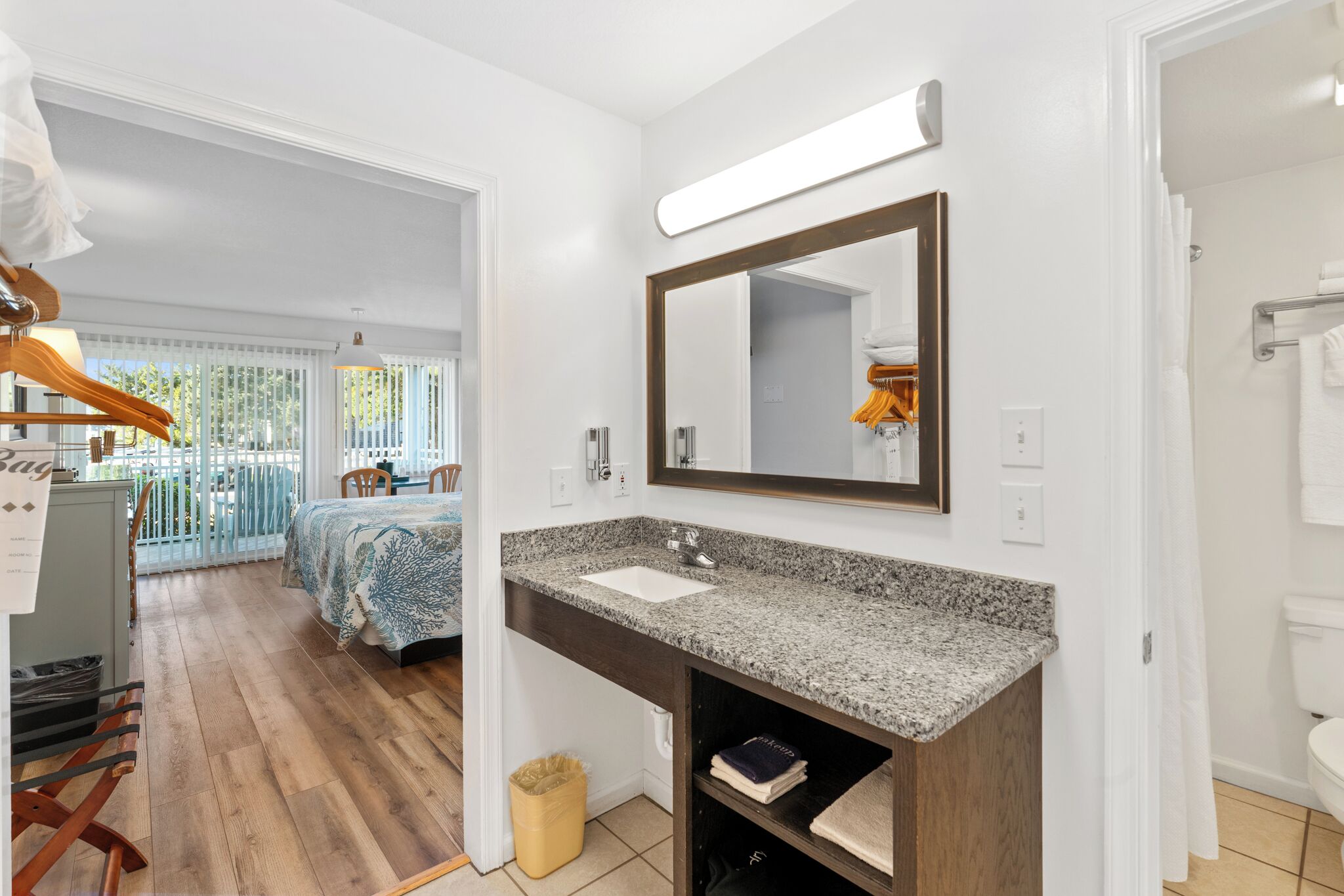 Une salle de bain moderne avec un comptoir en granit, un grand miroir et un rideau de douche.