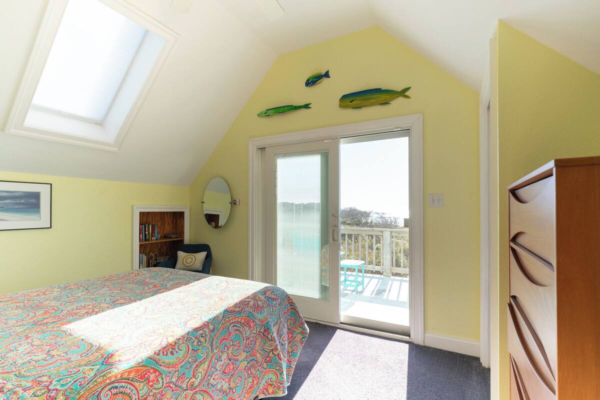 Ein Schlafzimmer mit einem Bett, einem Bücherregal, einer Tür, die auf einen Balkon führt, und Fischdekorationen an der Wand.