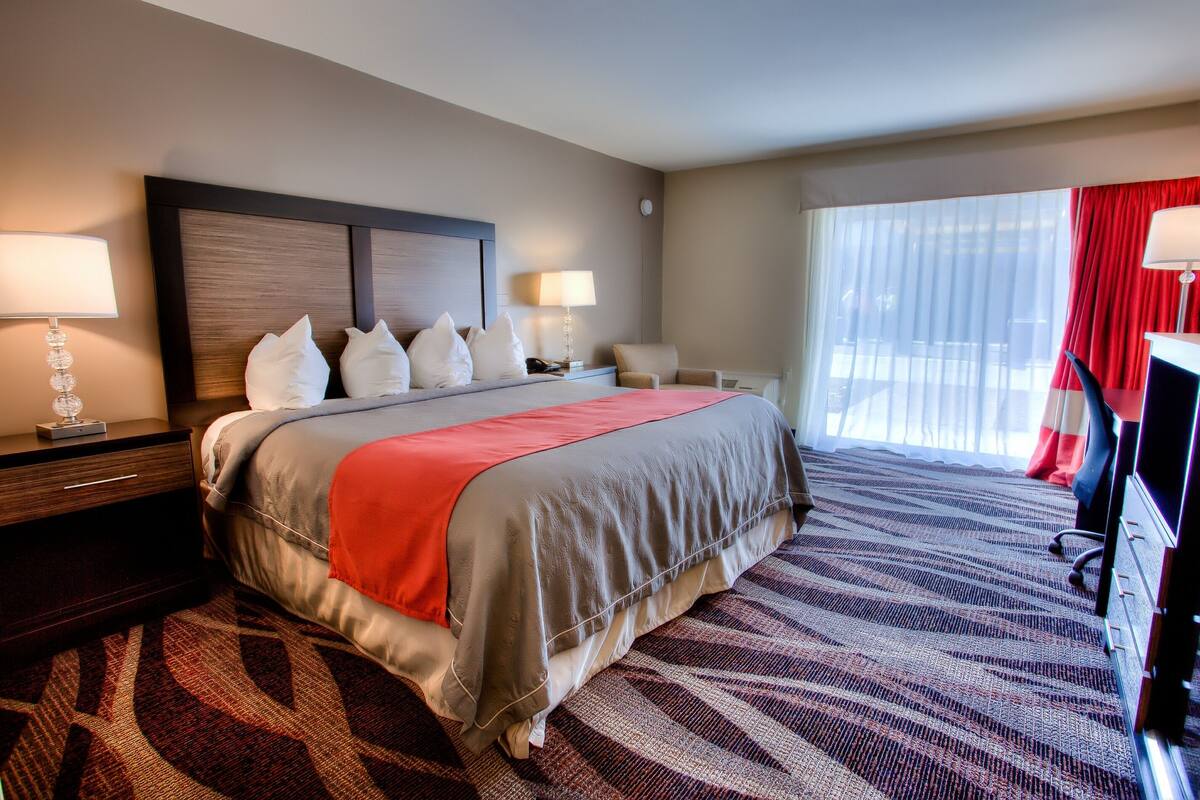 A hotel room with a large bed, two bedside tables, a desk, and a TV.