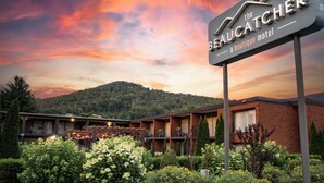 A motel with a sign reading "The Beaucatcher Boutique Motel" and a view of a mountainous landscape in the background. - The Beaucatcher – A Boutique Motel (Asheville)