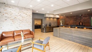 A modern lobby with a reception desk, a brown leather sofa, and a glass coffee table. - The Beaucatcher – A Boutique Motel (Asheville)