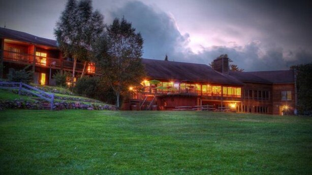 A large lodge with multiple guest rooms, a covered outdoor area, and a well-maintained lawn. - Lakewoods Resort & Lodge (Cable)