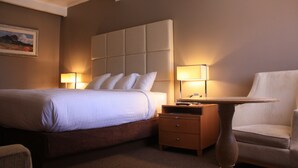 Une chambre d’hôtel avec un grand lit, une table de chevet avec une lampe, une chaise et une petite table.