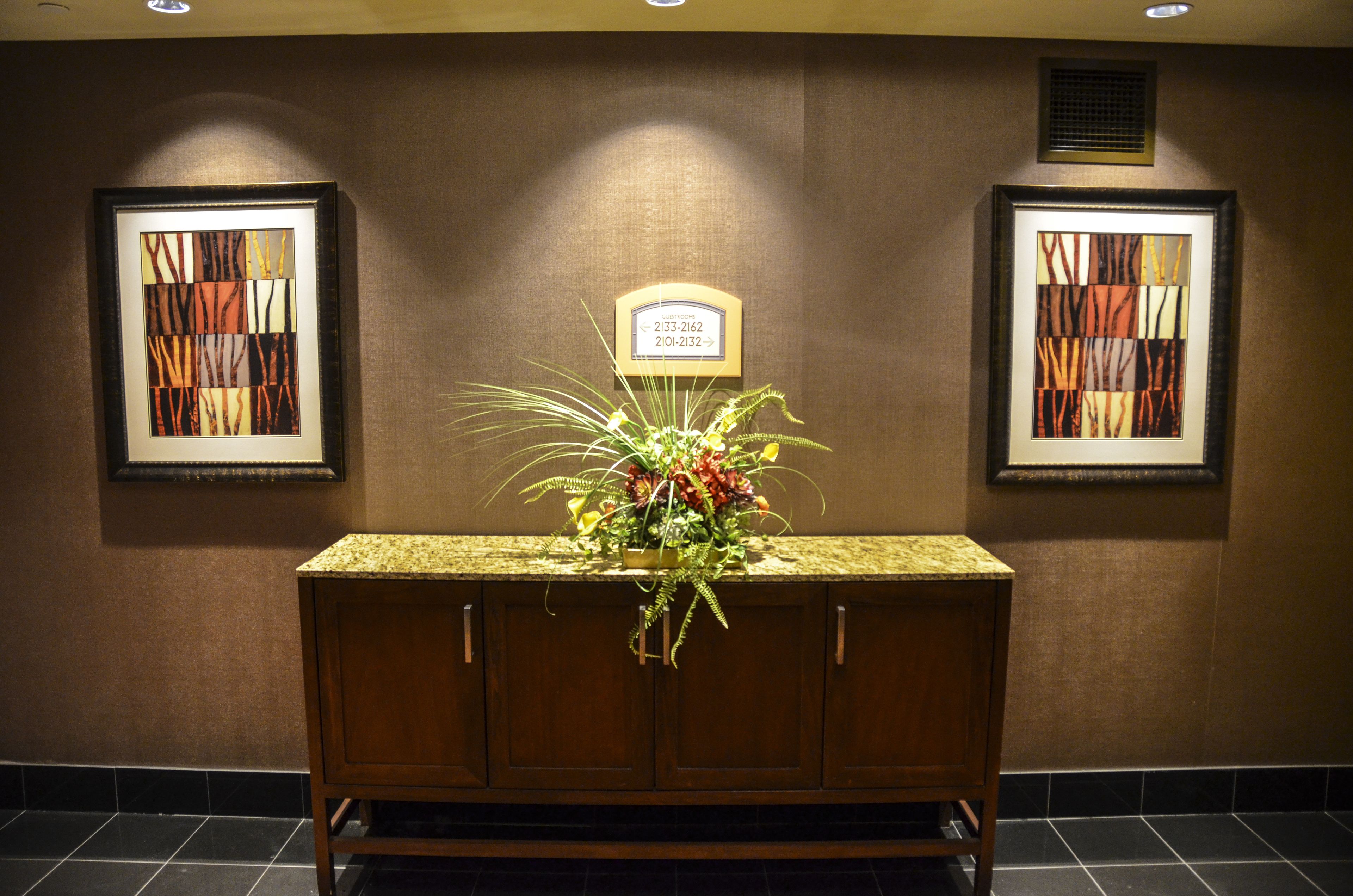 A reception area with a wooden counter, framed artwork on the walls, and a sign above the counter.