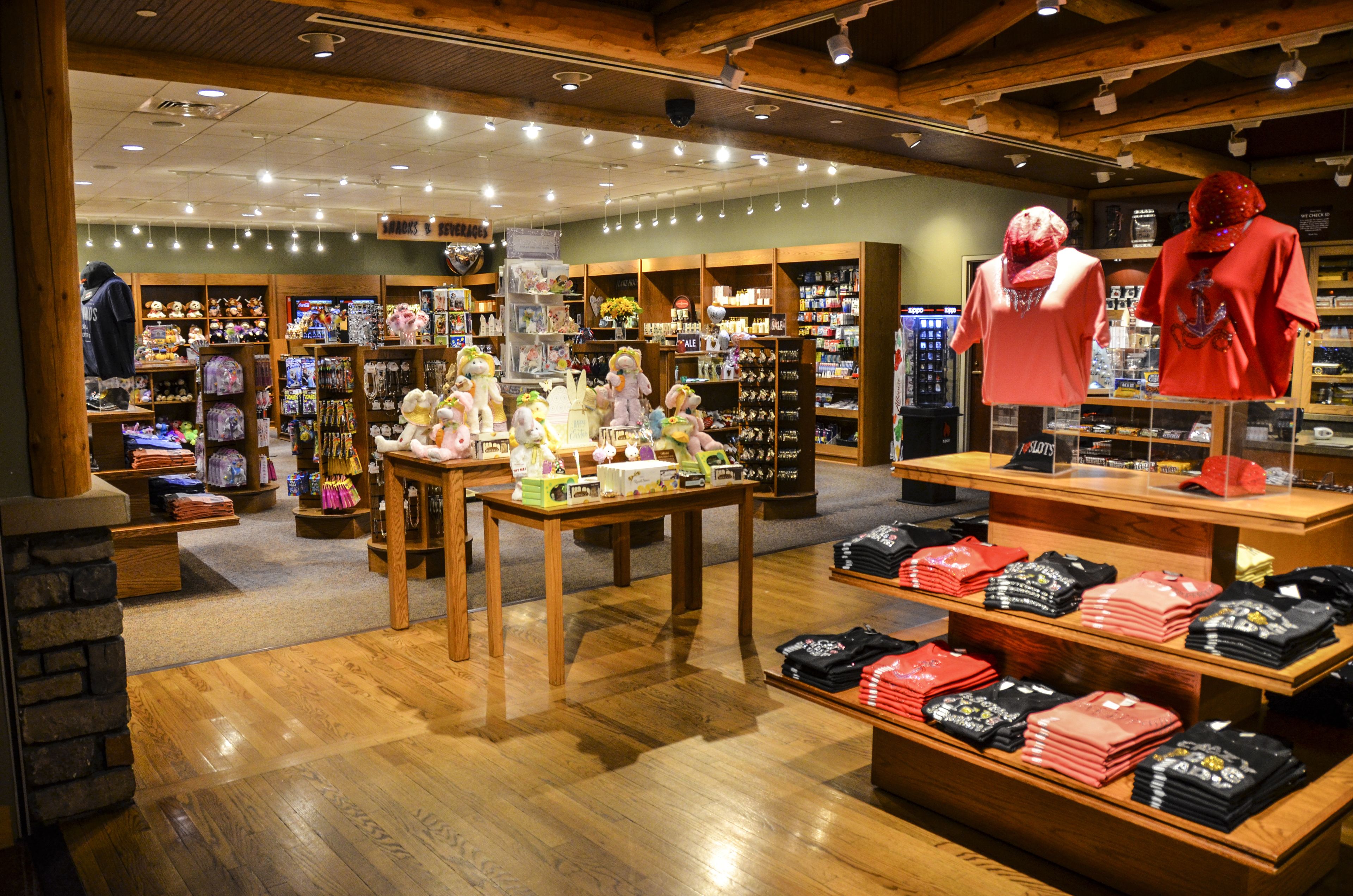 A retail store with wooden flooring and shelves stocked with various merchandise.