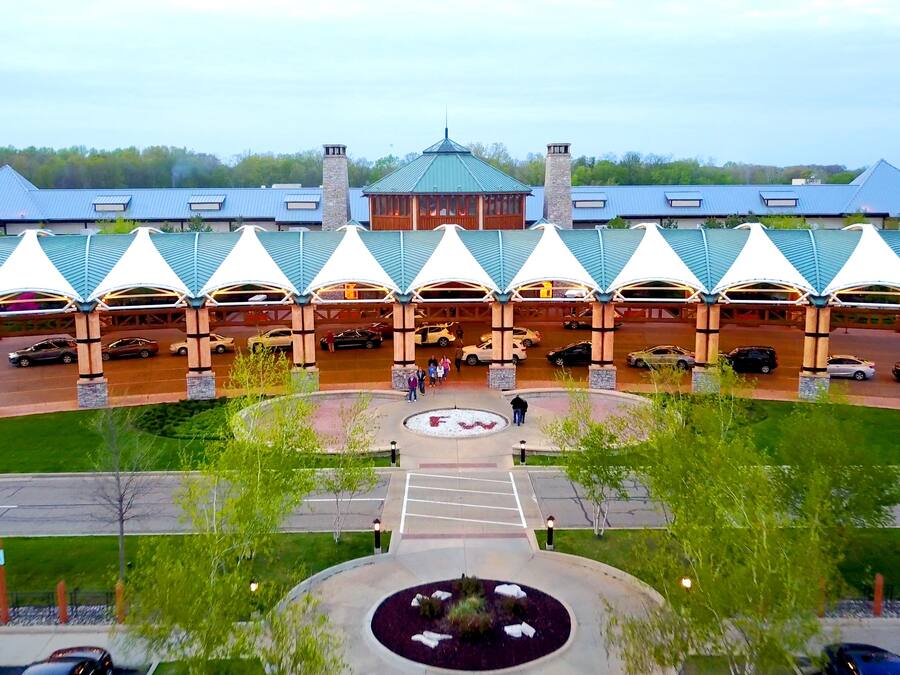 A hotel with a central atrium, multiple covered parking areas, and a landscaped entrance.