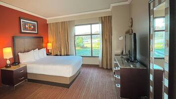 Habitación de hotel con una cama grande, televisión, escritorio con lámpara y ventana con cortinas.