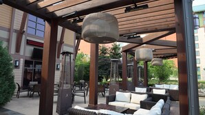 An outdoor patio area with wicker furniture, a pergola structure, and hanging lamps. - Four Winds Casino Resort – New Buffalo (New Buffalo)
