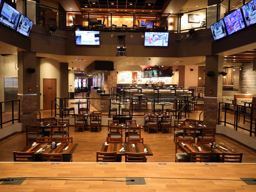Ein geräumiges Restaurant mit mehreren Essbereichen, einer Bar und verschiedenen Fernsehern, die Inhalte zeigen.
