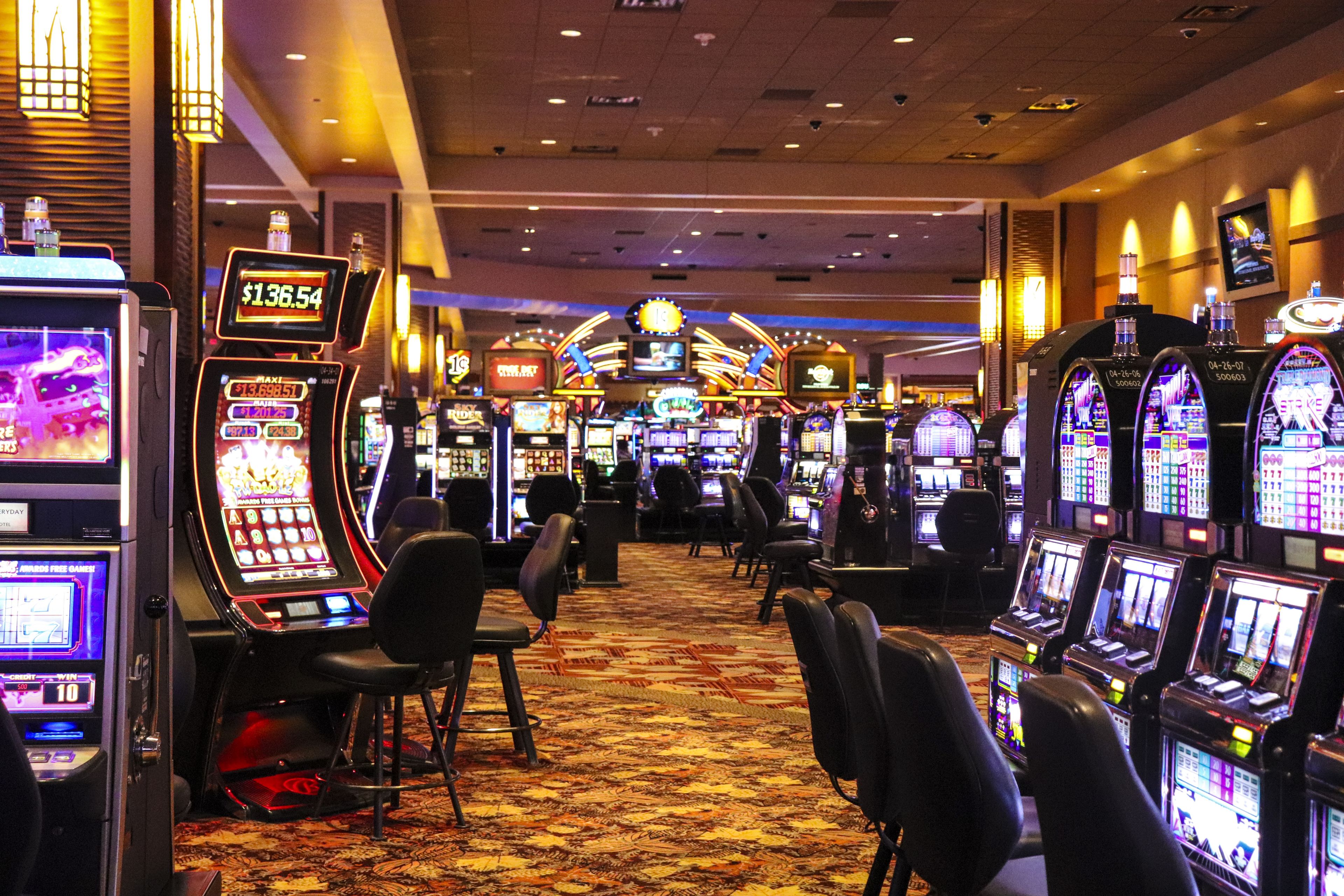 A casino with multiple slot machines and a carpeted floor.