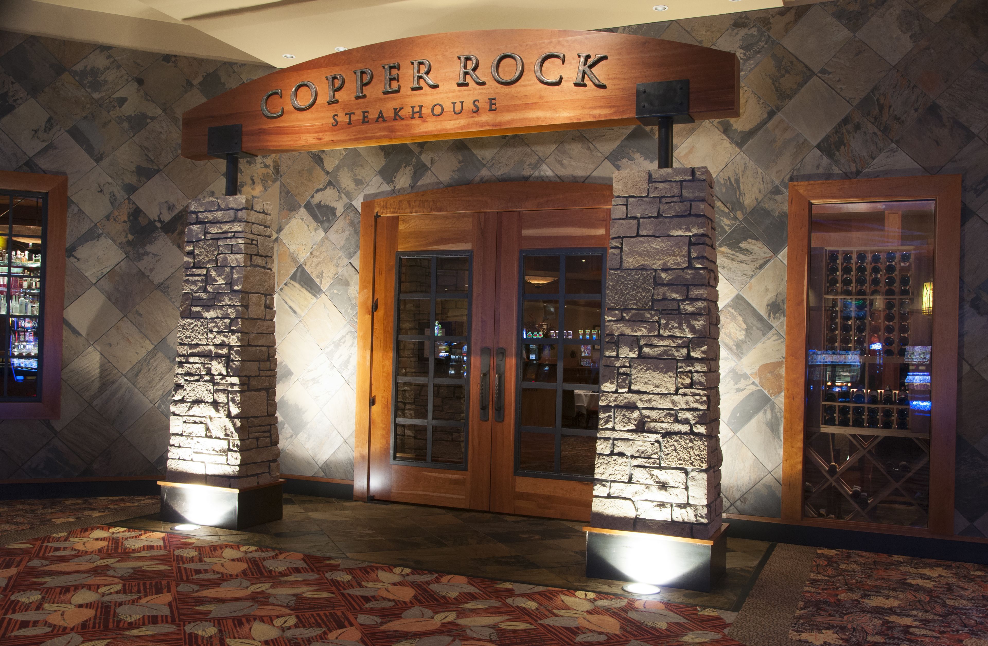 Entrada de un restaurante con fachada de piedra y un letrero que dice 'Copper Rock Steakhouse'.