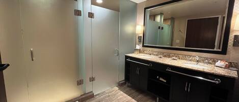 Un baño moderno con ducha de vidrio, un espejo grande y encimera de mármol.