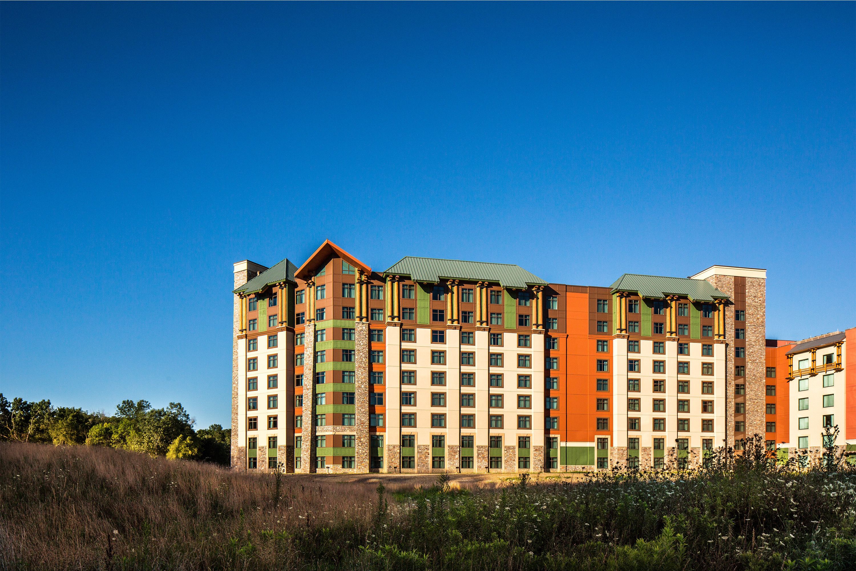 Ein mehrgeschossiges Hotel mit modernem architektonischen Design, das Ziegel- und Glasfassaden sowie ein markantes Gründach vereint.