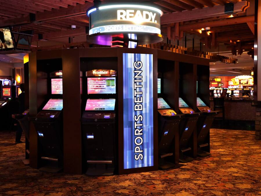 A sports betting area with multiple betting machines and a prominent 'SPORTS BETTING' sign.