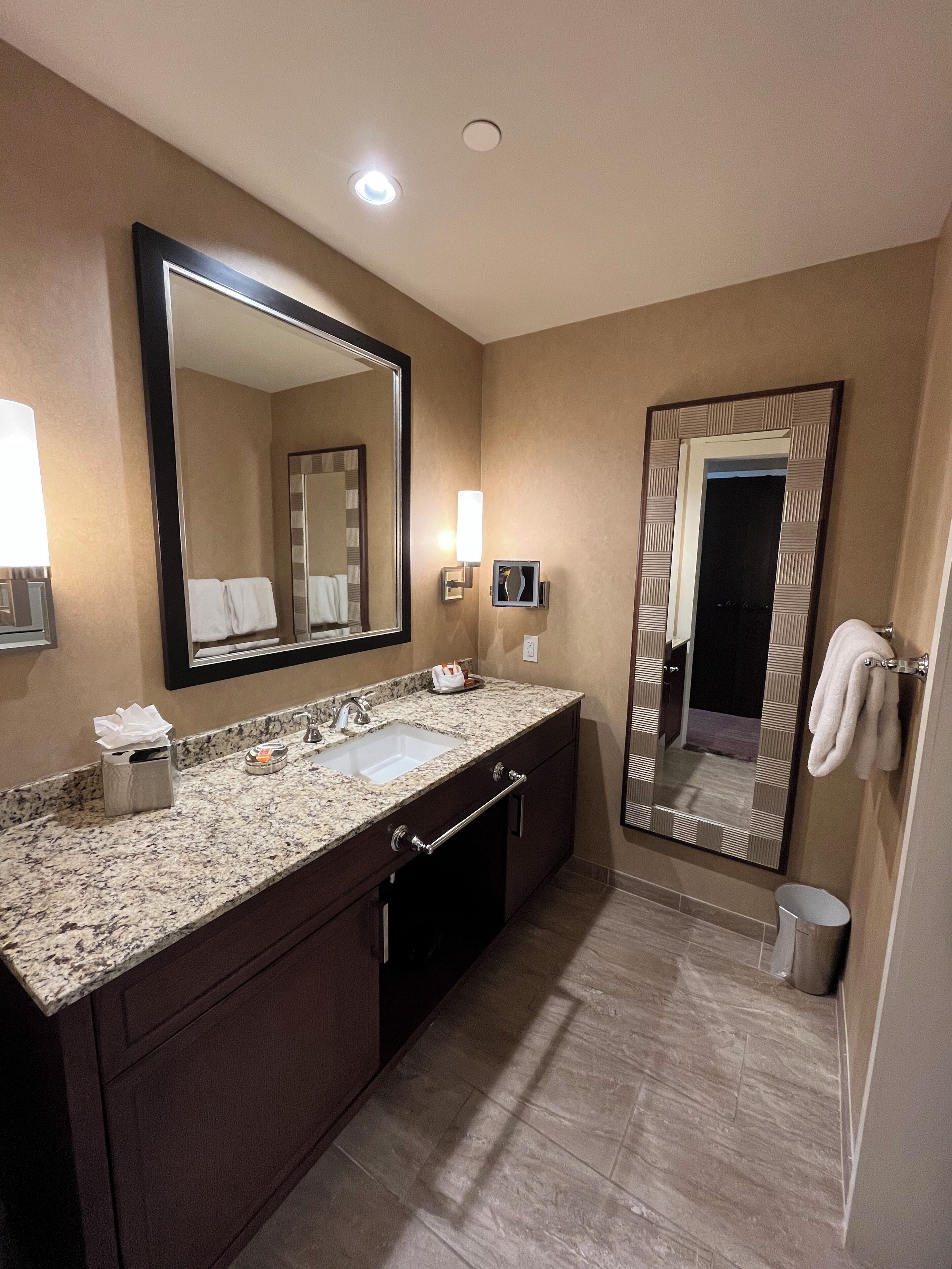 A modern bathroom with a large mirror, a sink, and a towel rack.