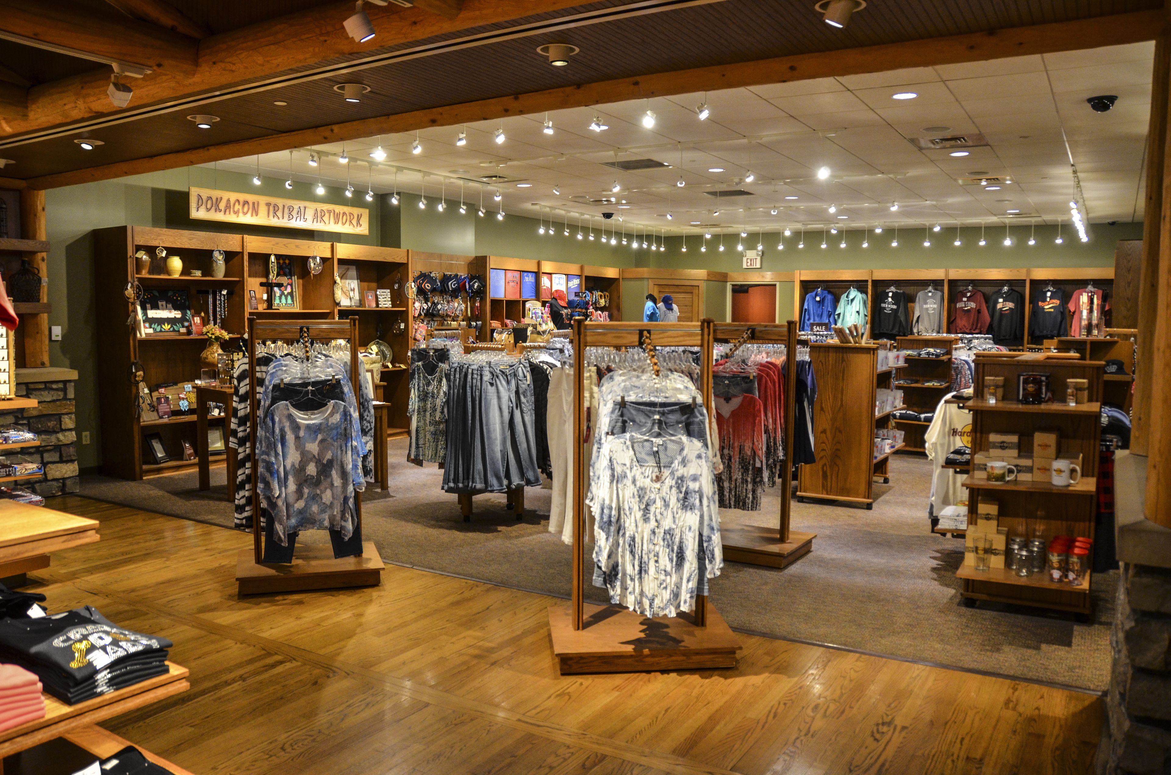 A clothing store with wooden flooring and a sign reading "Pokagon Tribal Artwork".